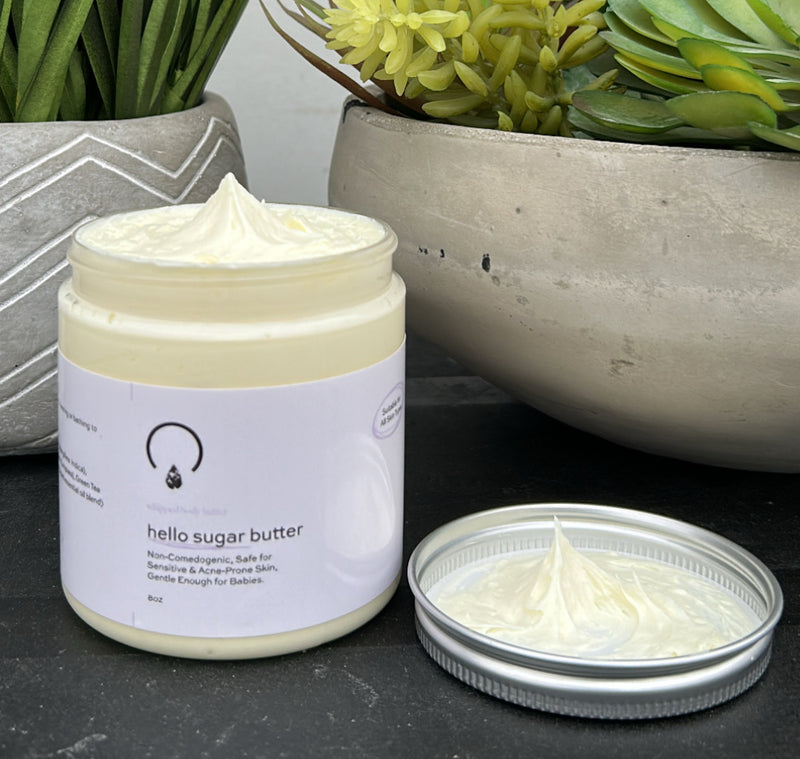 Hello Sugar Butter, a rich, whipped body butter designed to deeply hydrate, nourish, and protect your skin. Formulated with a luxurious blend of shea butter, mango butter, jojoba oil, olive oil, and green tea extract, this lightweight yet intensely moisturizing formula melts effortlessly into the skin, leaving it silky smooth without a greasy residue.