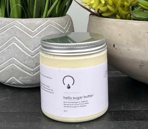 Hello Sugar Butter, a rich, whipped body butter designed to deeply hydrate, nourish, and protect your skin. Formulated with a luxurious blend of shea butter, mango butter, jojoba oil, olive oil, and green tea extract, this lightweight yet intensely moisturizing formula melts effortlessly into the skin, leaving it silky smooth without a greasy residue.